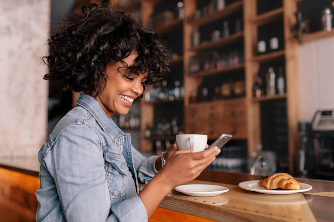 Woman smiling scheduling eye exam online on smart phone